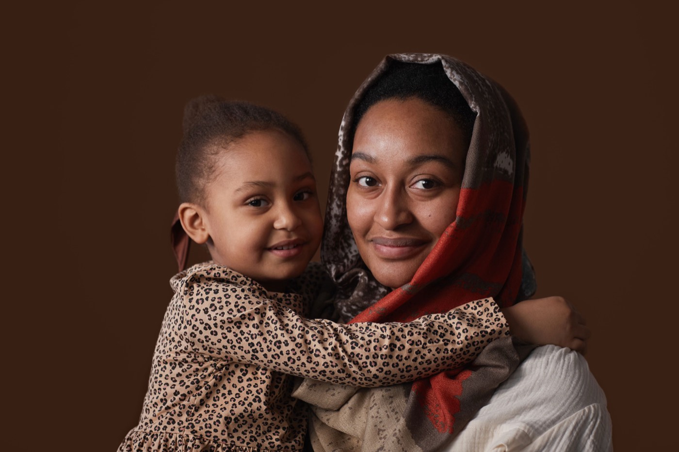 A mother holding her small child, both looking to camera